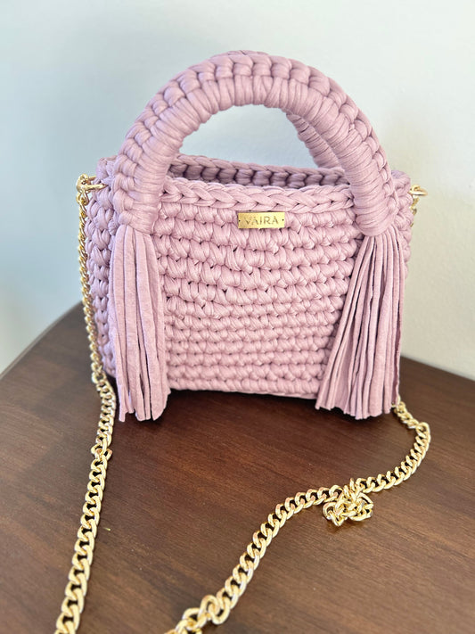 A true symbol of elegance, this handwoven shoulder bag features an exquisite braided design that adds texture and charm. Its shimmering gold chain elevates the look, offering a touch of luxury and versatility. Compact yet spacious, it fits all your daily essentials effortlessly. The standout clasp completes the design with flair, making it perfect from morning coffee to evening dinner.
