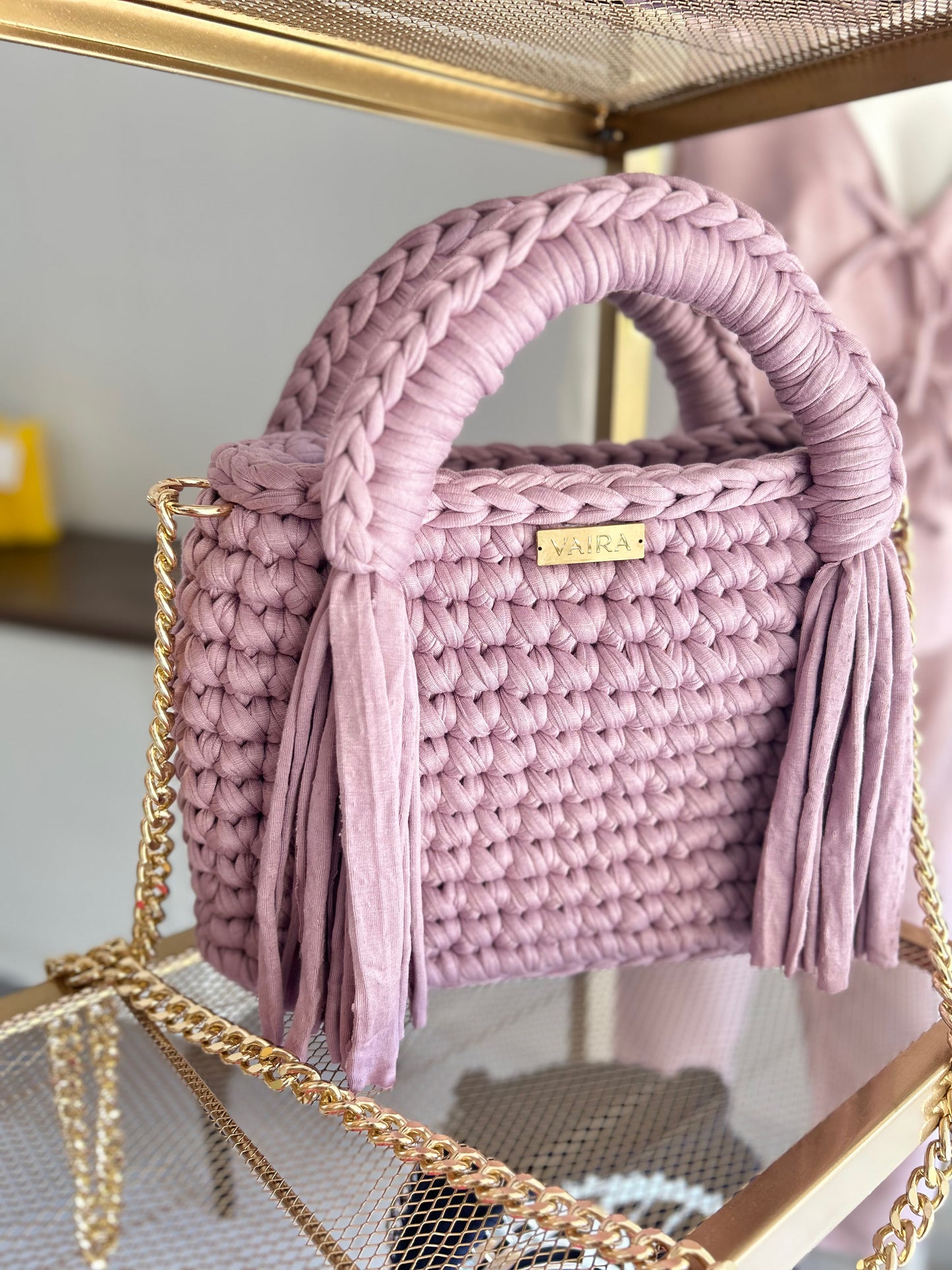 A true symbol of elegance, this handwoven shoulder bag features an exquisite braided design that adds texture and charm. Its shimmering gold chain elevates the look, offering a touch of luxury and versatility. Compact yet spacious, it fits all your daily essentials effortlessly. The standout clasp completes the design with flair, making it perfect from morning coffee to evening dinner.