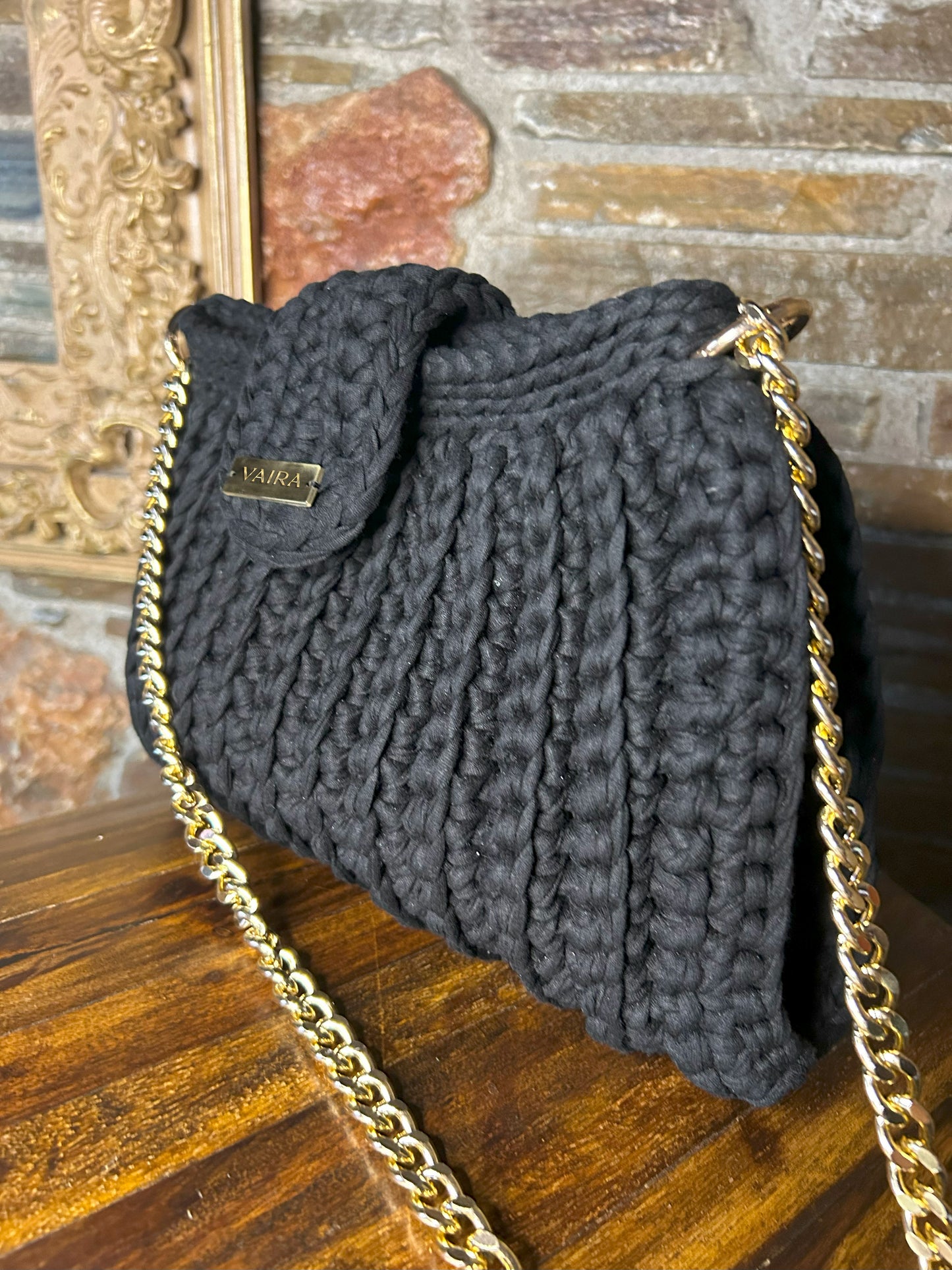 Handmade black crochet shoulder bag, featuring a gold chain strap, side keychain, zipper closure, and inner lining