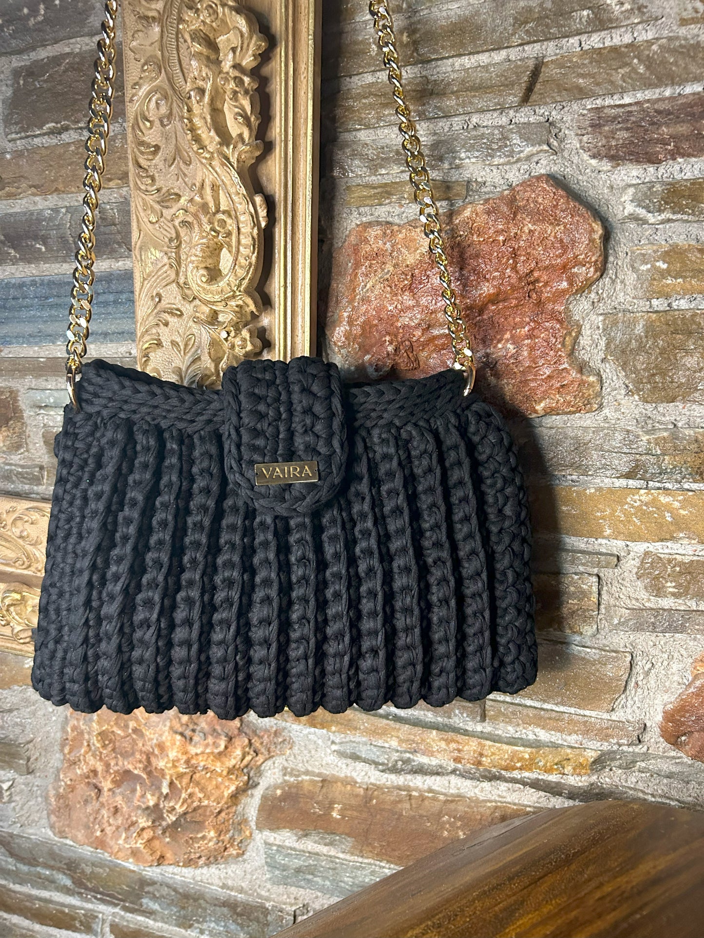 Handmade black crochet shoulder bag, featuring a gold chain strap, side keychain, zipper closure, and inner lining