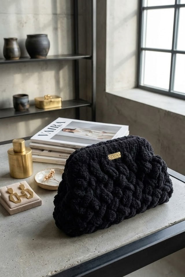 Κομψό πλεκτό clutch Puffy Muse τοποθετημένο σε καλαίσθητο περιβάλλον με περιοδικά μόδας και χρυσά αξεσουάρ. Μια statement τσάντα για γυναίκες που αγαπούν το ιδιαίτερο design. Πλεκτή τσάντα χειρός Puffy Muse της VAIRA. Χειροποίητη κατασκευή με μαλακή, αφράτη υφή και χρυσό λογότυπο. Το απόλυτο αξεσουάρ για chic εμφανίσεις.